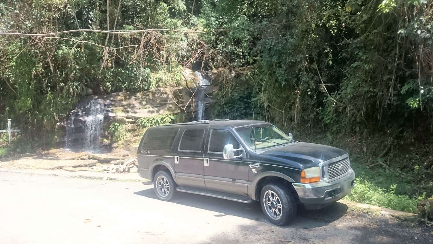 La Ford Excursion en una carretera de montaña, junto a una caída de agua.