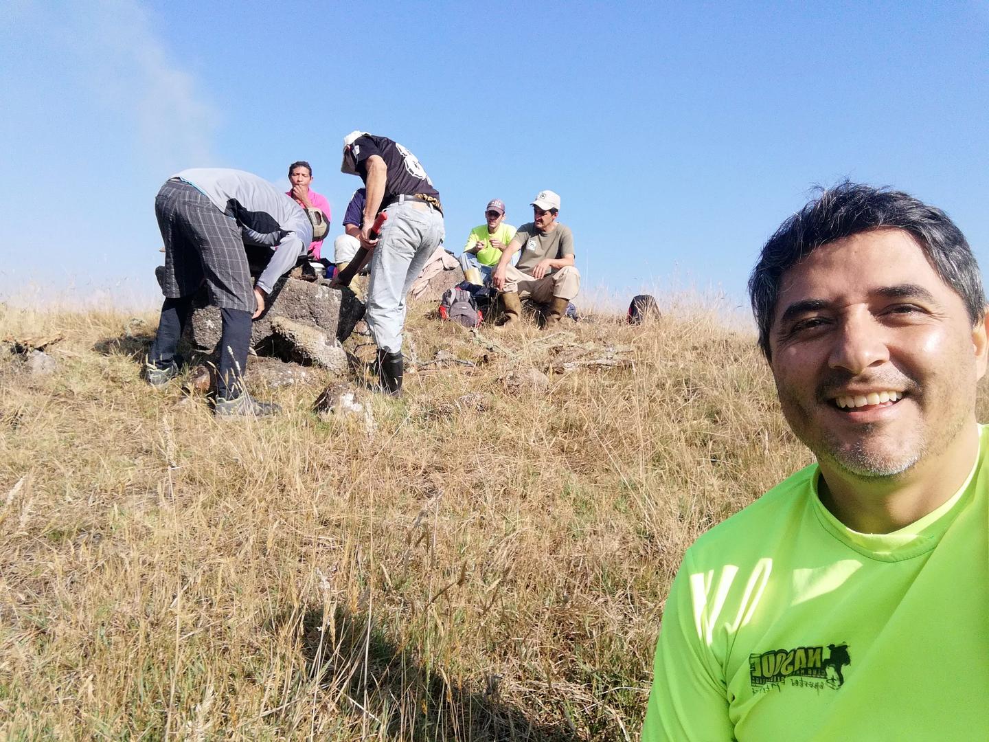 Freddy sonríe en primer plano; detrás, el grupo junto al fogón.