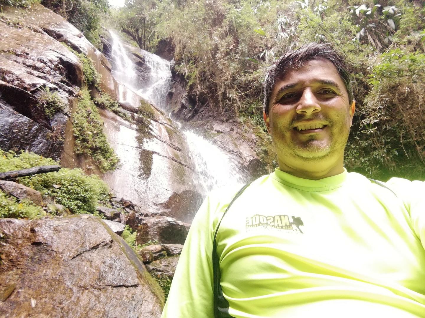 Freddy sonríe frente a la cascada.