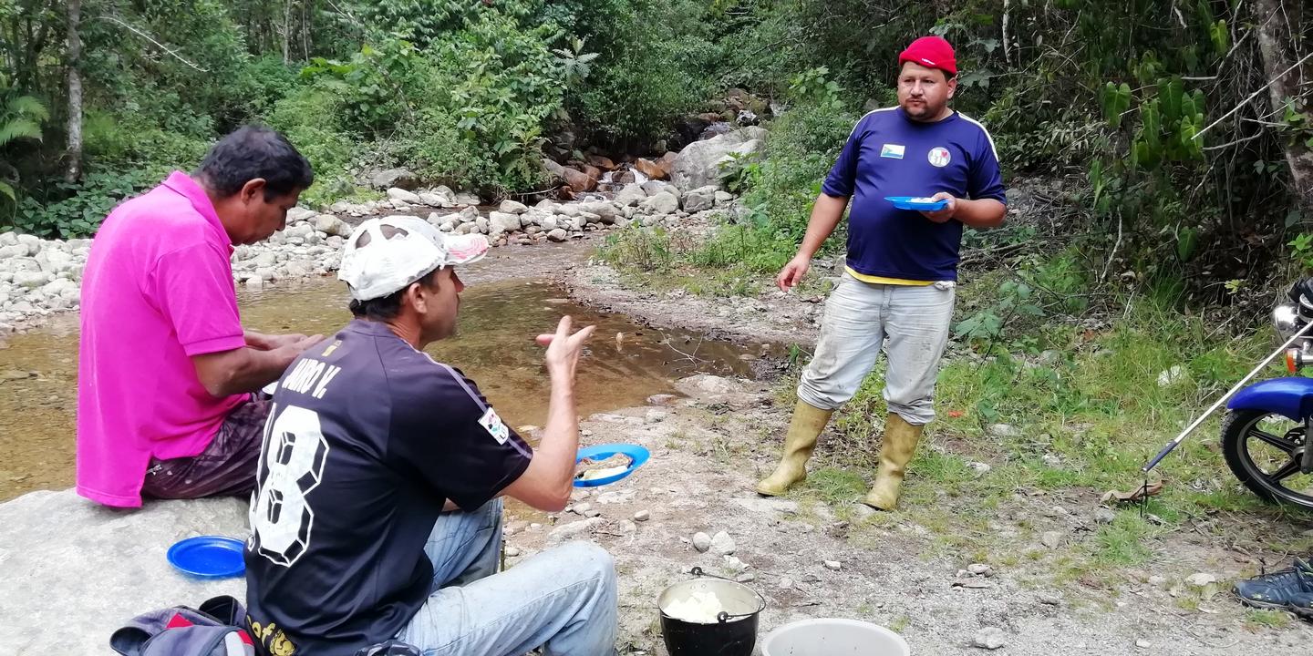 Parte del grupo come sentado en las piedras de un río.