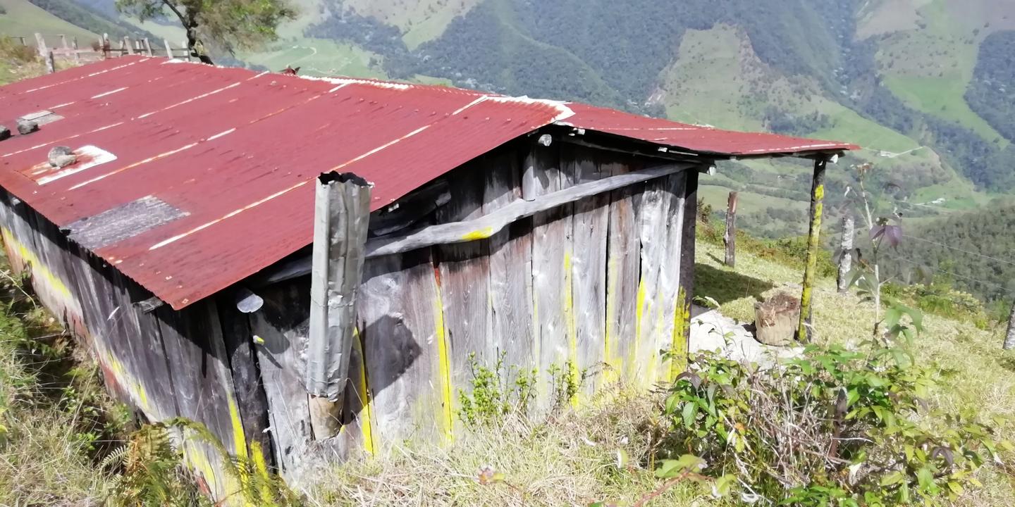 Una casa de madera con techo rojo en una ladera.