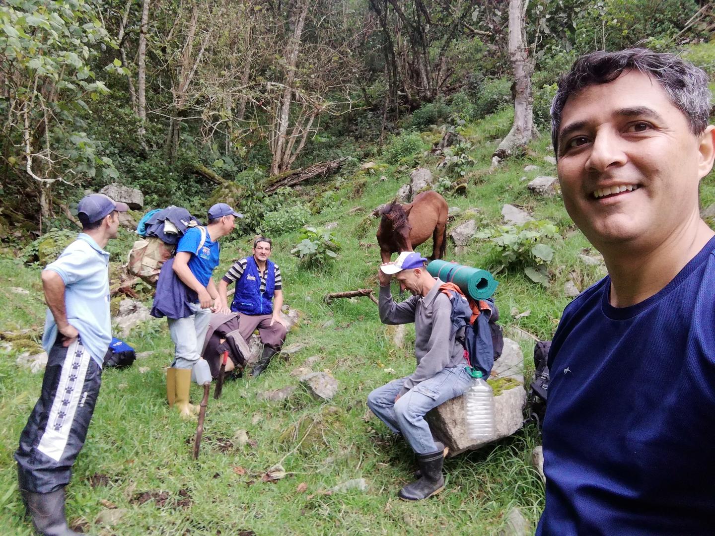 El grupo descansa en una ladera con un caballo detrás.