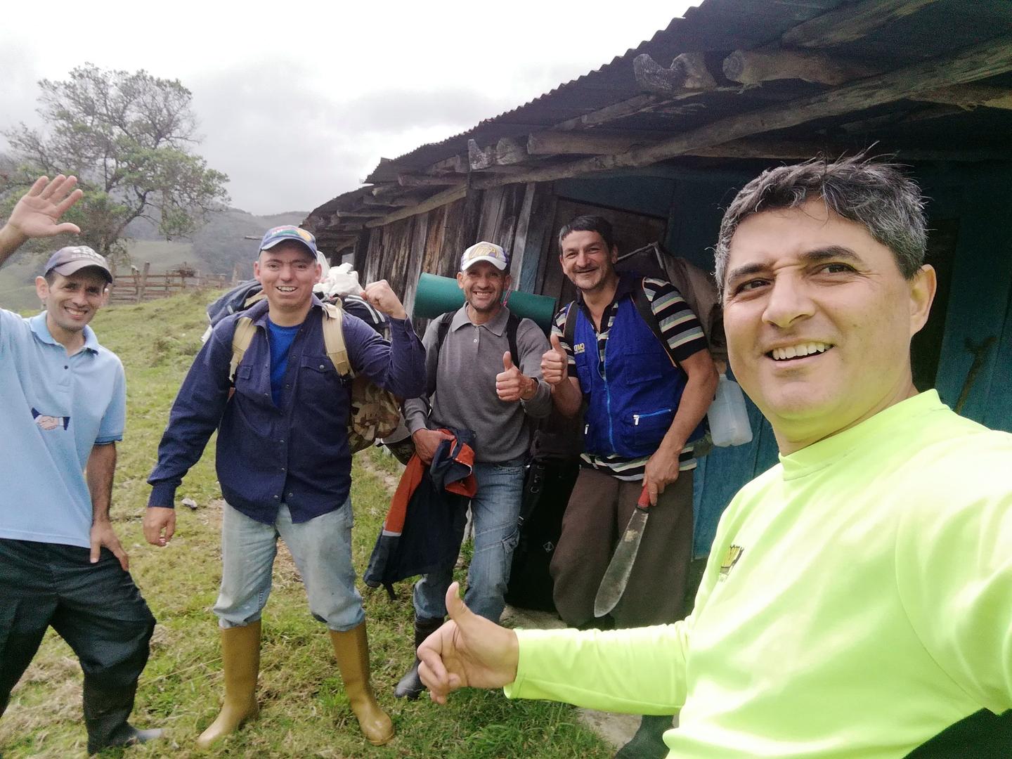 Los cinco expedicionarios sonríen frente a un rancho de madera.