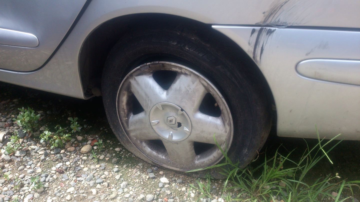 La rueda trasera del Mégane desinflada, con la carrocería rayada.