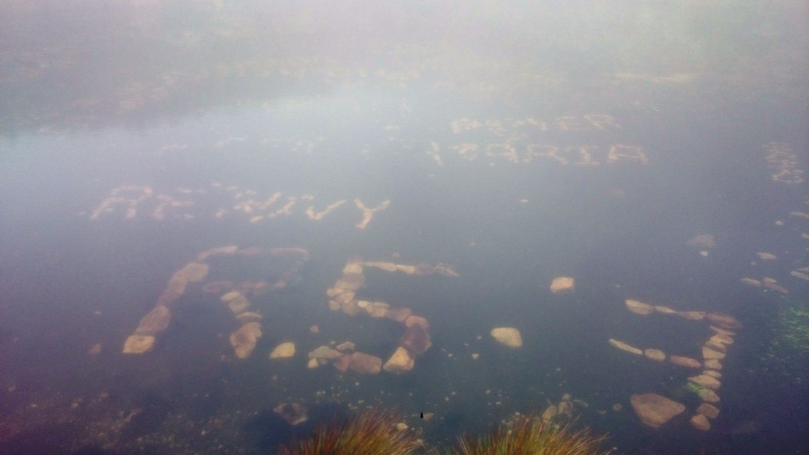 Nombres escritos con piedras en una laguna, ahora cubiertos de agua.