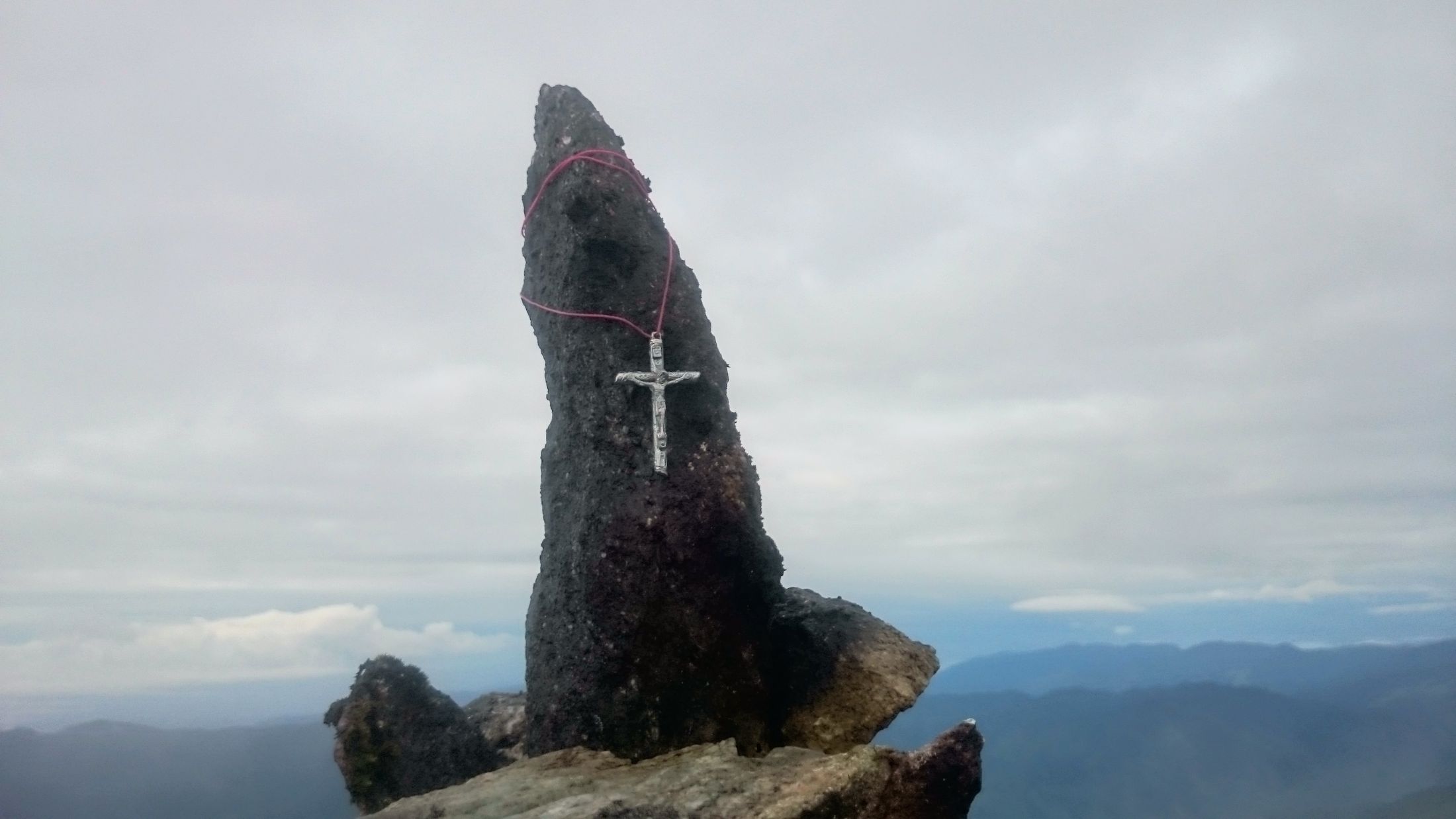 La laja con el crucifijo en la cima del Pico San José, con las montañas de fondo.
